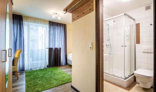 La salle de bains est pourvue d'une douche, de toilettes et d'un tapis vert. dans l'établissement Schroeders City-Style-Hotel, à Trèves