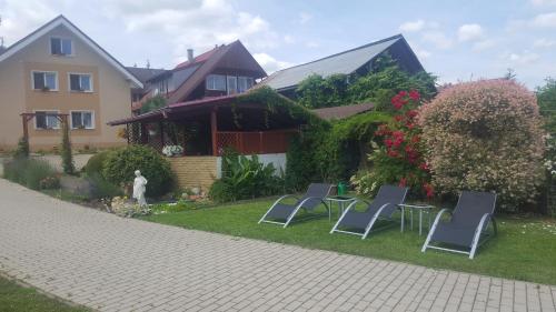 a yard with three chairs and a house at Penzion Mirabel in Bešeňová