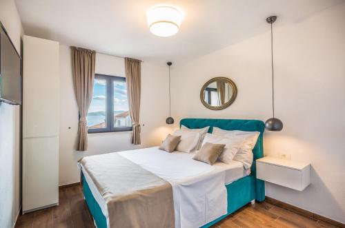 a bedroom with a bed with a green headboard and a mirror at Apartmani Arapovic in Baška Voda