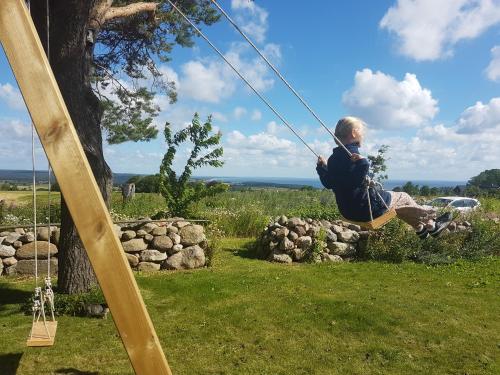 a man is swinging on a swing at Bästekille Gårdshotell in Kivik