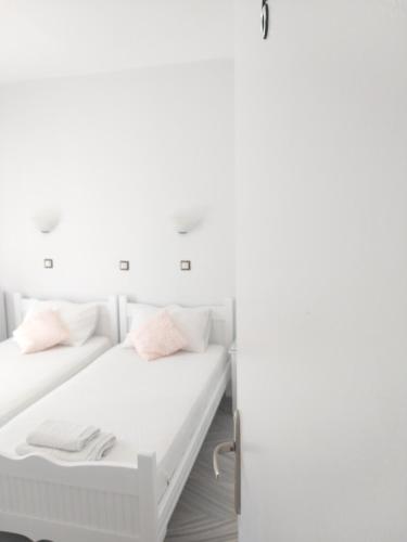 a white room with two beds and a refrigerator at Syrianos Hotel in Naxos Chora