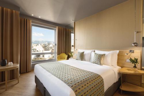a bedroom with a large bed and a large window at Wyndham Grand Athens in Athens