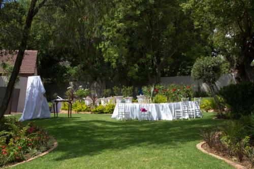 a table with white chairs in a yard at Classique Grace Boutique Hotel in Johannesburg