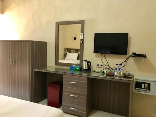 Habitación con escritorio, TV y espejo. en Anoi Itam Resort en Sabong