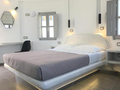 uma cama num quarto branco com uma janela em Argonaftes em Firostefani