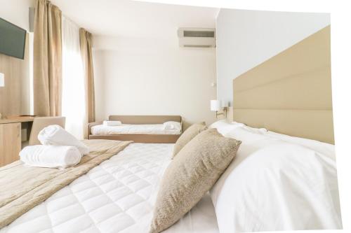 a bedroom with a large bed with white sheets and pillows at Hotel Loreley in Lido di Jesolo