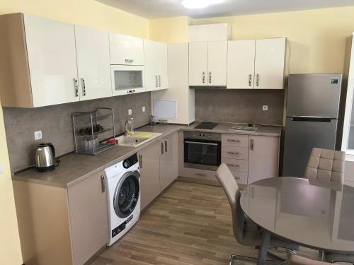 une cuisine avec des armoires blanches et une table et une machine à laver dans l'établissement Jane Guest House, à Nessebar