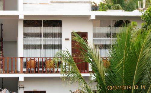 un bâtiment blanc avec des chaises sur un balcon dans l'établissement The Amora, à Baie d'Arugam