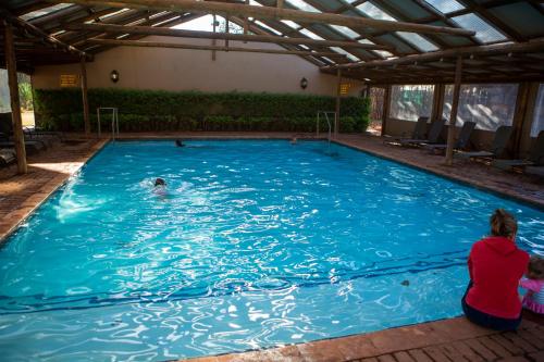 a woman sitting in front of a swimming pool at Makhato Bush Lodge 111 in Bela-Bela