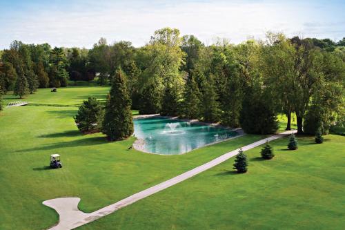 a green lawn with a lake and trees at Oakwood Resort in Grand Bend