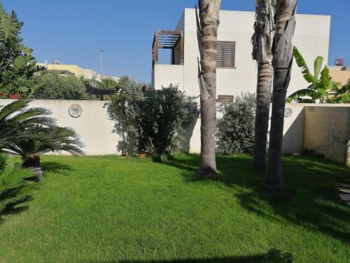 une cour avec des palmiers et un bâtiment dans l'établissement Villa Favignana, à Favignana