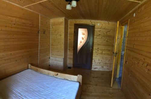 a empty room with a bed in a wooden room at Sadyba Domashniy zatyshok in Pilipets