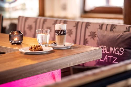 a table with two cups of coffee and a cookie at Hotel Glockenstuhl in Westendorf