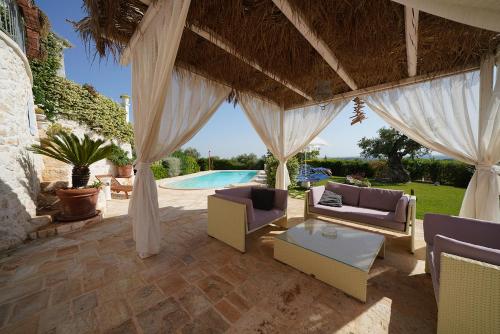 an outdoor patio with a pavilion with chairs and a pool at Villa Belvedere in Ostuni