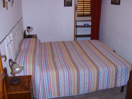 a bedroom with a bed with a striped bedspread at Bed & Breakfast 5 Di Spade in Gioiosa Marea