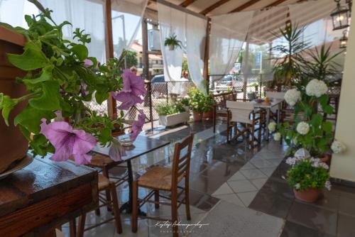 ein Restaurant mit Tischen und Stühlen mit lila Blumen in der Unterkunft Premier Sea Apartment in Palaió Tsiflíki