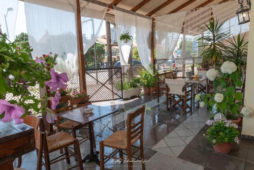 ein Restaurant mit Tischen, Stühlen und Pflanzen in der Unterkunft Premier Sea Apartment in Palaió Tsiflíki