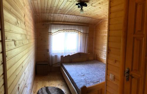 a small room with a bed in a log cabin at Sadyba Domashniy zatyshok in Pilipets