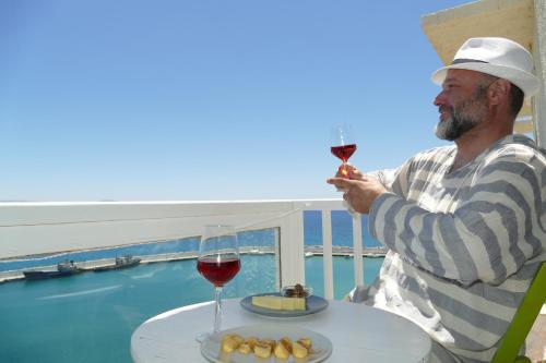 Ein Mann, der mit einem Glas Wein am Tisch sitzt. in der Unterkunft Galini Mare in Agia Galini