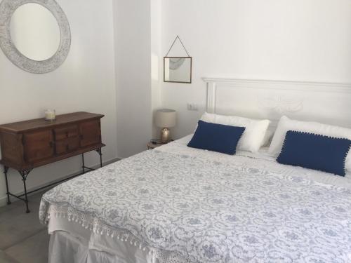 a bedroom with a bed with blue pillows and a mirror at El nido del Chorro in Málaga