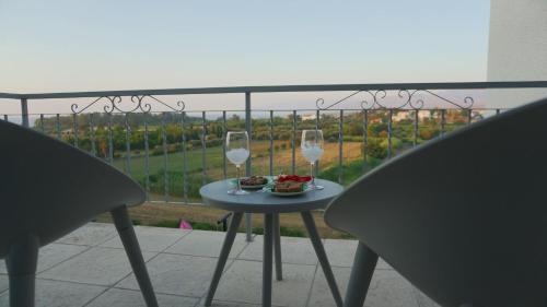 a table with two glasses of wine on a balcony at Panoramic sea view apartment in Polis-Latchi in Polis Chrysochous