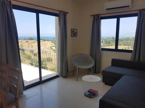 a living room with a couch and large windows at Panoramic sea view apartment in Polis-Latchi in Polis Chrysochous