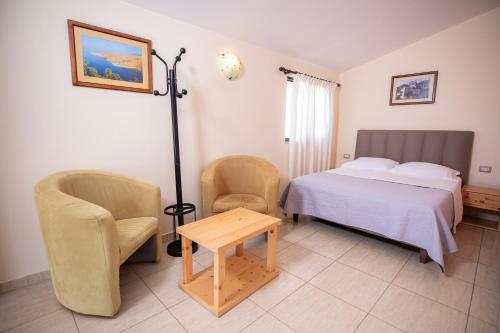 a bedroom with a bed and two chairs and a table at Chalet Ambel in Dhërmi