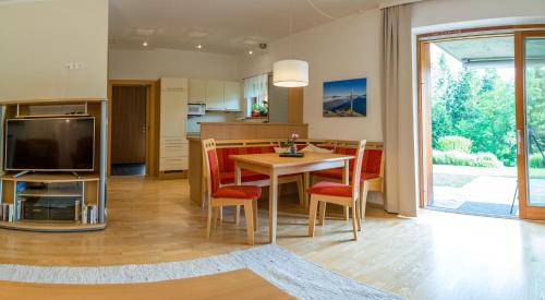 a kitchen and living room with a table and chairs at Gartenlodge Auszeit in Nötsch