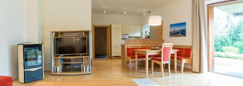 a kitchen and living room with a table and a television at Gartenlodge Auszeit in Nötsch