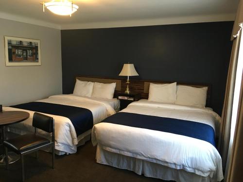 a hotel room with two beds and a table with a lamp at Falls Manor Resort in Niagara Falls