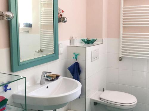 een badkamer met een wastafel, een toilet en een spiegel bij Haus am Hagen in Friedland