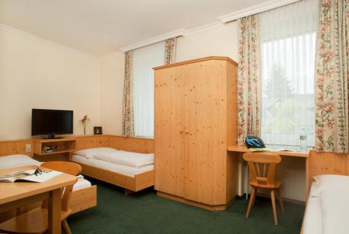 a hotel room with a bedroom with a bed and a tv at Hubertushof Fromwald Hotel und Gasthof in Bad Fischau