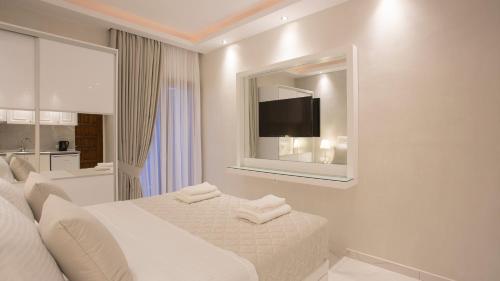 a white bedroom with a bed and a tv on the wall at Amaryllis Luxury Rooms in Platamonas