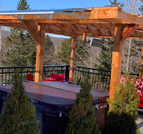 a wooden pergola with a table on a patio at Le Loft Riverstone CITQ 3O1849 in Saint Pierre de Broughton