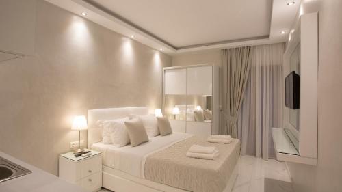 a white bedroom with a bed with two towels on it at Amaryllis Luxury Rooms in Platamonas