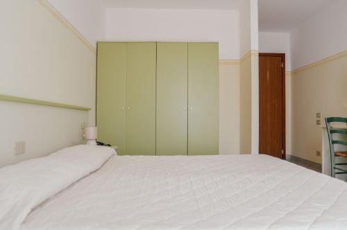 a bedroom with a white bed and green cabinets at Hotel Club i Pini - Residenza d'Epoca in Versilia in Lido di Camaiore