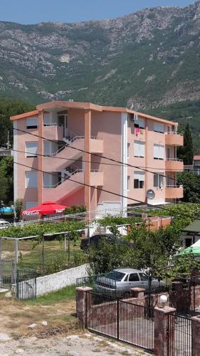 a pink building with a car parked in front of it at Apartments Music in Sutomore