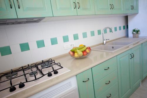 a kitchen with green cabinets and a bowl of fruit on the counter at Villa Rosato in Selva di Fasano