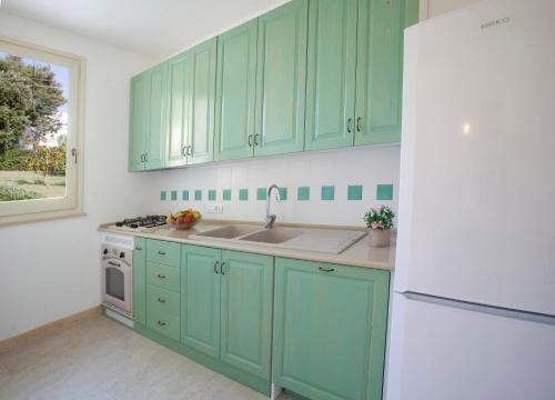 a kitchen with green cabinets and a white refrigerator at Villa Rosato in Selva di Fasano