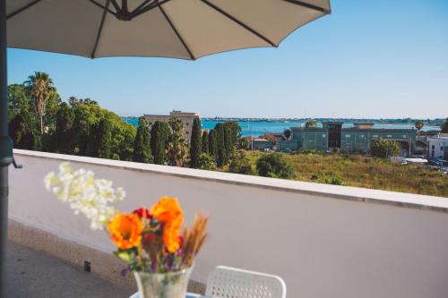 a vase of flowers sitting on a table with an umbrella at Hotel Como in Siracusa