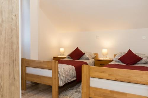 two beds in a room with two lamps on tables at Apartman Mirko in Otočac
