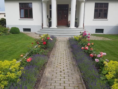 a brick path leading to a white house with flowers at Moltke-Villa in Teterow