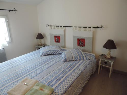 ein Schlafzimmer mit einem Bett mit blauer Decke und 2 Lampen in der Unterkunft Les Cigales d'Estoublon in Estoublon