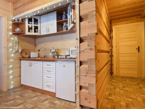 a kitchen with white cabinets and a wooden wall at Góralski domek in Ząb