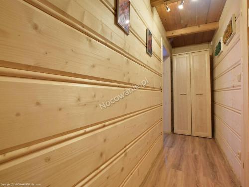 pasillo de la cabaña de madera con paneles de madera y armario en Góralski domek en Ząb