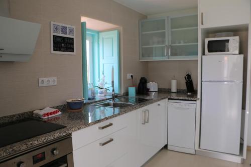 a kitchen with white cabinets and a white refrigerator at Casinha Verde in Nadadouro