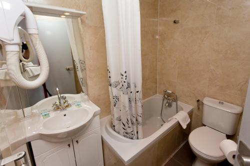 a bathroom with a tub and a sink and a toilet at Hipotel Paris Belgrand Mairie du 20ème in Paris