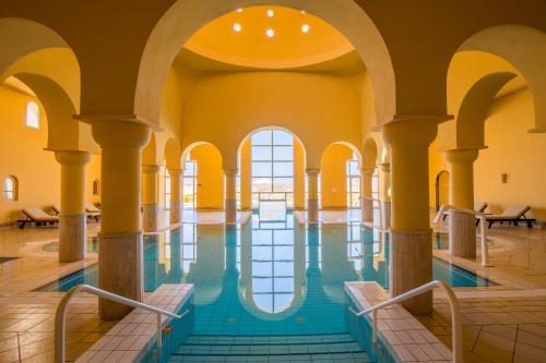 a pool in a building with columns and water in the middle at Ulysse Thalasso & Spa - All Inclusive in Houmt Souk