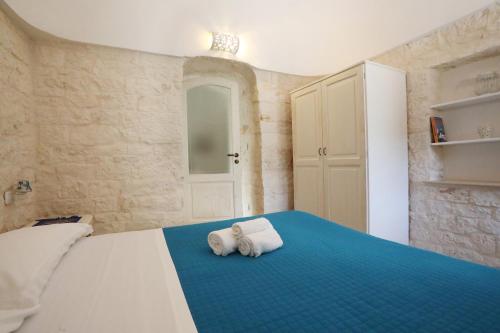 a bedroom with a blue bed with towels on it at Villa Rosato in Selva di Fasano