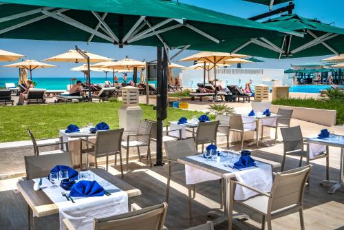 a restaurant with tables and chairs with the beach in the background at Ulysse Thalasso & Spa - All Inclusive in Houmt Souk